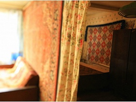 коричневый шкаф для одежды, кровать у стены с ковриком в спальне, смежной с гостиной жилого дома в деревне