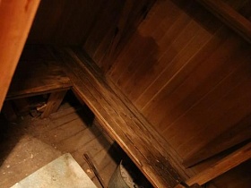 маленькая деревянная комната с низкими скамейками у металлической печки с камнями в лачуге отшельника у маленького озера