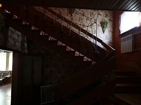 деревянная лестница с веревочной сеткой между перилами в прихожей загородного дома