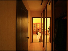 одежда на тремпелях в шкафу-купе с зеркальными дверцами в узком коридоре типичной двушки в жилом доме