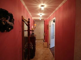 новогодний веночек , большое зеркало в деревянной рамке на стене и деревянная напольная вешалка в розовой прихожей семейной трешки