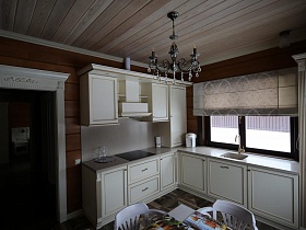 раковина с краном у деревянного окна с жалюзи кремового цвета в кухне съемного коттеджа