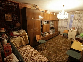 икона и крест на верху  мебельной стенки с посудой и телевизором, стулья, диван и кресла, белый шкаф у окна со светлыми шторами зала квартиры СССР 80-89гг стиля