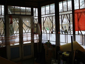 рабочий инвентарь в углу, зеркало у входной двери застекленной веранды деревянной советской дачи художника с овальной террасой