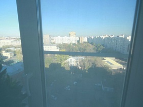 вид из окна квартиры оператора на жилой квартал с высотками и  зелеными насаждениями