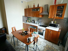 коричневый мебельный гарнитур , белая газовая плита с вытяжкой на кухне квартиры в переезде(въезде) молодоженов