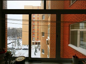 вид из окна семейной трехкомнатной квартиры на окна соседних квартир современного двухцветного кирпичного дома в жилом квартале