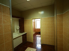 санузел в школе с бежевой плиткой на стенах и коричневой на полу