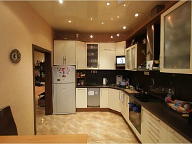 общий вид кухни с подвесным потолком и молочного цвета мебельной стенки в простой просторной современной квартиры Север 2 с детской