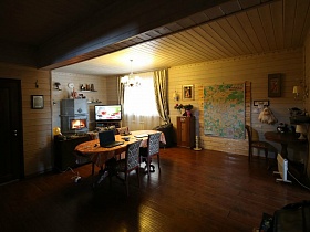общий вид гостиной с камином,телевизором и большим столом в современном деревянном доме