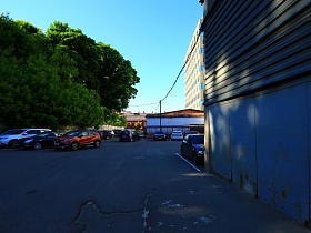металлический ангар на территории бизнесцентра с асфальтированным двором и припаркованными машинами