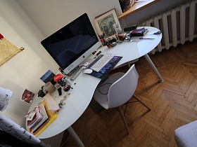 блокноты,папки, канцтовары, икона на белом угловом столе с ноутбукои и клавиатурой,белый стульчик со спинкой на полу светлой комнаты современной и советской квартиры в одном помещении