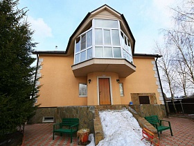 дом на высоком цоколе , с большим стеклянным балконом и зелеными скамейками по обе стороны лестницы