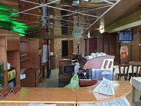 зеркальный потолок в баре с аквариумом, табличками, салфетницами, кофе машинкой с кружками на верху на коричневой столешнице барной стойки