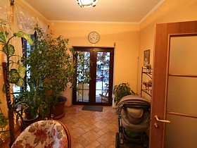 детская коляска, многочисленные комнатные растения у окон в холле лесной дачи