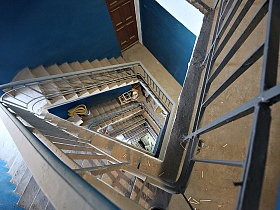 лестничные маршы из 10 ступеней интересной по архитектуре винтовой лестницы в подъезде с синими стенами жилого дома в Москве