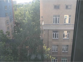 вид из окна спальной комнаты на соседние высотные жилые дома в жилом квартале с зелеными деревьями