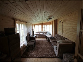 мягкая мебель на ковре в гостинной с большими окнами на деревянной даче у реки  на дороге