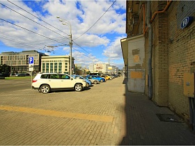 машины на парковочных местах у жилого здания на Садовом
