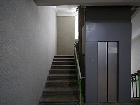 светло-серые стены лестничных пролетов и площадок с лифтами на этажах жилого дома