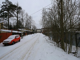 длинная дорога вдоль дачных домов в зимнее время