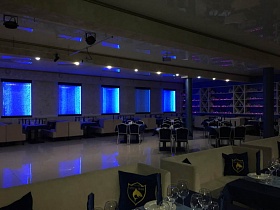 неоновая синяя подсветка на окнах с закрытыми жалюзи просторного зала уютного ресторана в синих цветах