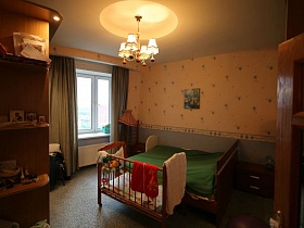 детский манеж у деревянной кровати во взрослой спальне