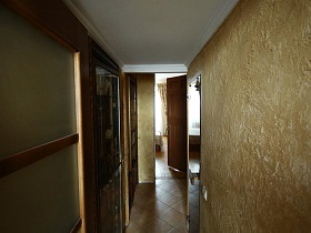 большое зеркало на бежевой стене длинного коридора с белым потолком советской трехкомнатной квартиры
