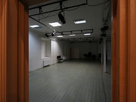 вид из раздевалки с коричневой дверью и стенами в белый просторный балетный зал в столичном здании театра