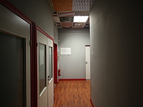 серые стены длинного коридора с белыми дверьми со стеклянными вставками конферензала и офисных кабинетов