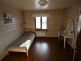 картина на стене над деревянной кроватью с леопардовым покрывалом, гримерный белый столик с круглым зеркалом в спальне современного деревянного трехэтажного дома