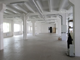 огромное производственное помещение с белыми колонами на белом кафеле и белым потолком с деревянным блочным перекрытием