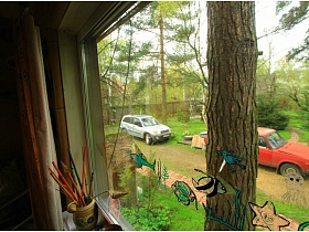 легковые машины на дорожке большого зеленого участка дачи в 2 дома из окна гостиной