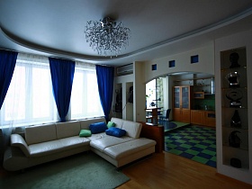 большой белый угловой диван с синими и зелеными подушками в гостинной