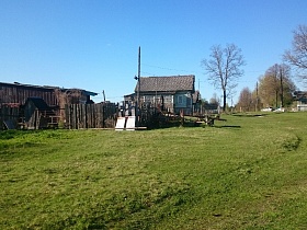 дом с верандой на высоком цоколе, деревянный колодец, длинный сеновал на участке за покосившемся забором на краю старой деревни 2