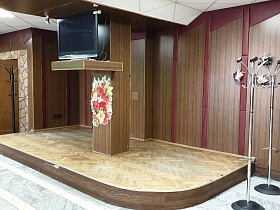 напольные круглые вешалки для одежды у подиума у панельной стены с большим телевизором на полке у квадратной колоны в столовой СССР