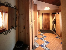 зеркало в металлической кованной рамке у деревянного шкафа в длинном коридоре с мозаичной плиткой семейной классической дачи