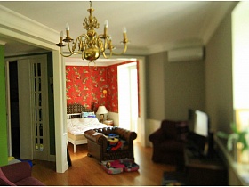 коричневое кресло на границе совмещенных зон спальни и гостиной в однокомнатной квартире жилого дома