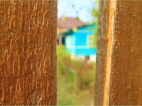 голубая дача СССР и здание новостройки из желтого кирпича сквозь штакетный деревянный забор