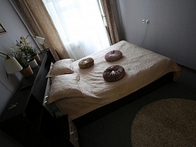 прикроватны круглый коврик у большой черной кровати с круглыми подушками