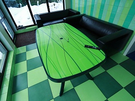 зеленая поверхность прямоугольного стола на фигурных ножках, черные диваны у салатовой стены и большого окна летней яркой кухни дома с частичным недостроем для съемок кино