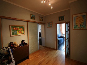 яркие красочные картины на светлых стенах просторного холла с открытыми дверьми в комнаты современной квартиры ИКЕА стиль