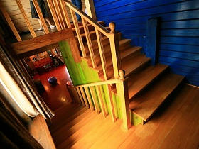 деревянные ступени лестницы с деревянными поручнями в современном двухэтажном зеленом загородном доме - избе