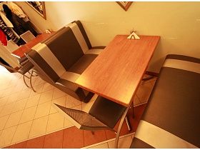 салфетница, баночки для специй на коричневых столах, мягкие двухцветные диваны у бежевой стены небольшого зала уютного кафе на берегу озера