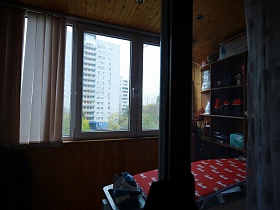 гладильная доска с утюгом, открытый шкаф с полками на застекленном балконе с жалюзи на окне трехкомнатной актерской квартиры