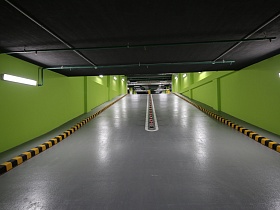 лампы дневного света на ярко зеленых стенах вдоль двухполосной гладкой дороги с разделителем посередине просторного современного цветного паркинга