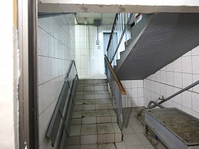 белая плитка на стенах лестничной площадки в подъезде на первом этаже жилого дома
