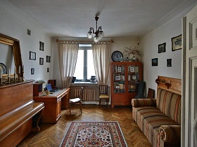 фотографии в рамках на стене над рабочим столом и диваном с деревянной спинкой в гостиной сталинки