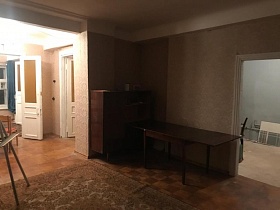 сервант и разложенный полированный стол в углу гостиной с белым мольбертом на коричневом цветном ковре квартиры на Остоженке