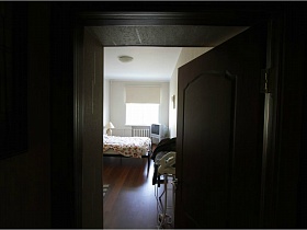 белье на гладильной доске за открытой дверью в спальную комнату трехкомнатной квартиры педагога